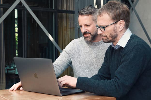 Timo Müller und Andreas Wroblewski arbeiten zusammen an einem Laptop